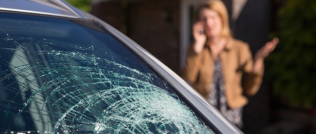Woman on phone next to cracked auto glass