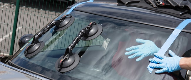 Technician adjusting new windshield into place in a car