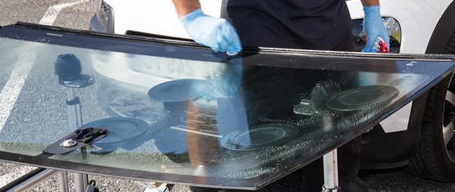 Technician cleaning windshield before installation