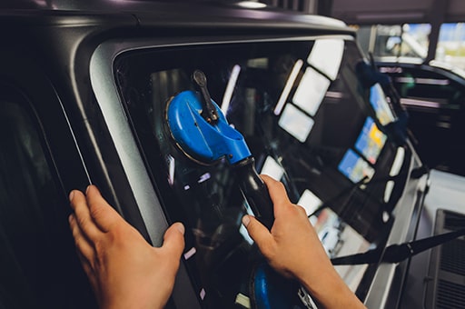 View of technician placing new windshield in modern SUV