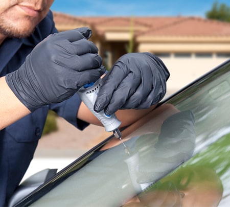Technician injecting resin into windshield damage