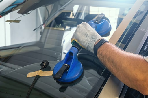 Technician placing new windshield on vehicle