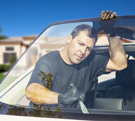 Technician taking old windshield off car